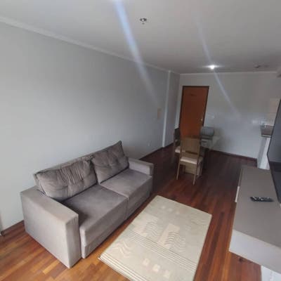 Sala com sofá, mesa de jantar, televisão, piso em madeira, iluminação natural