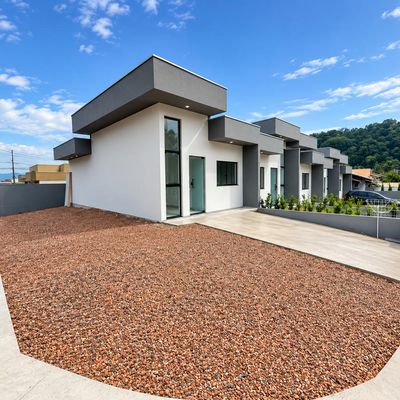 Fachada de casa com acabamento moderno em branco e cinza, área externa